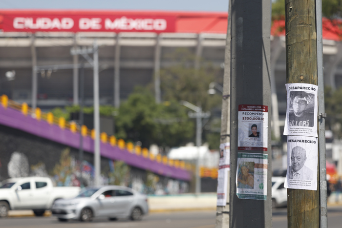 Familias de desaparecidos pegan fichas de búsqueda en el Estadio inaugural del Mundial